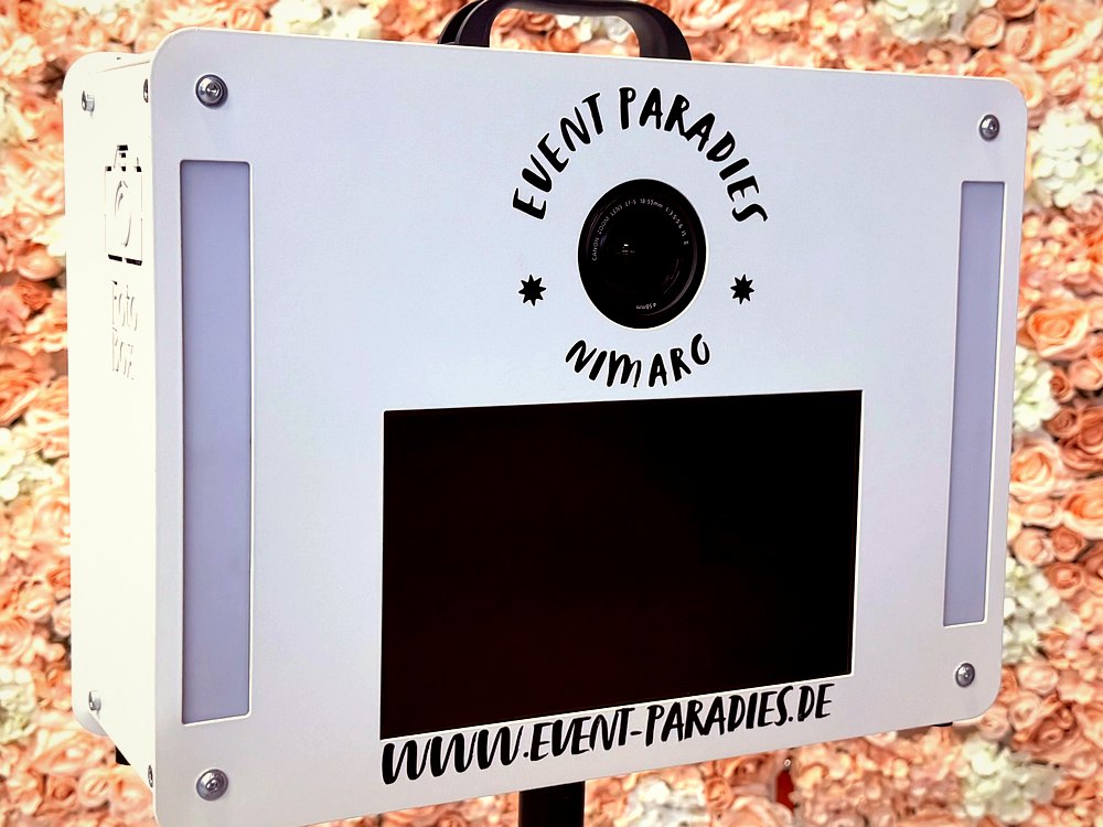 Weiße Fotobox von Event Paradies mit Branding und Kamera vor Blumenwand – Fotobox mieten Berlin & Brandenburg